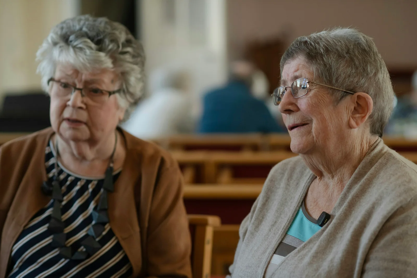 Two older women sit together at a table and talk.