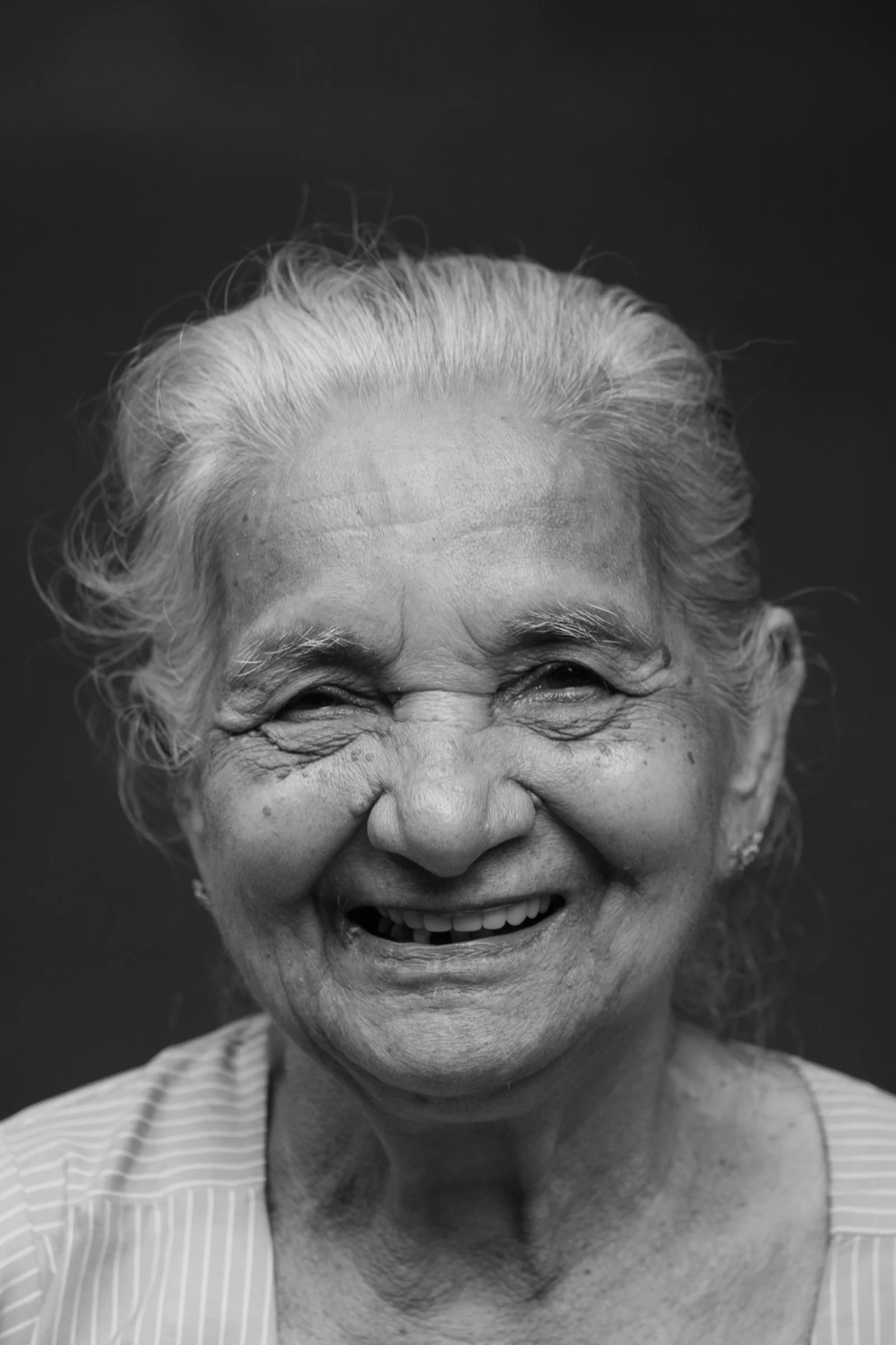 An older woman smiles in a close-up portrait.